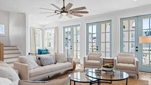 Un soggiorno spazioso con un ventilatore a soffitto, ampie finestre e vista sulla città.