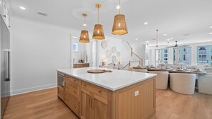 Un'ampia cucina con un'isola grande, mobili in legno e luci a sospensione.