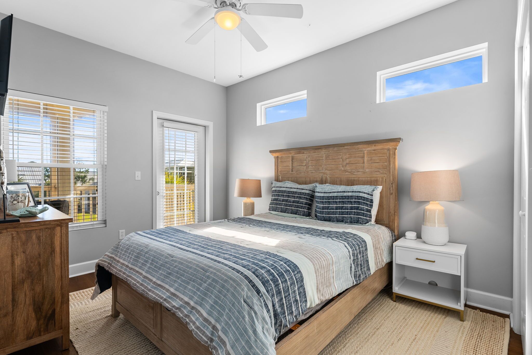 A bedroom with a bed, bedside tables, a ceiling fan, and windows.