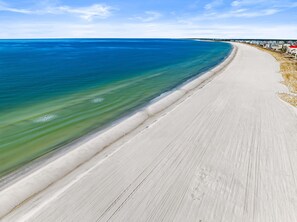 Ein weiter, sandiger Strand mit klarem, blauem Wasser und einer langen Küstenlinie.