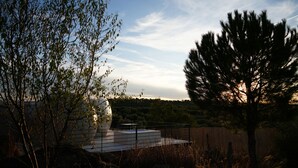 A modern outdoor area with a seating area, surrounded by trees and a view of a distant landscape. - Panoramic Suites (Guadamur)