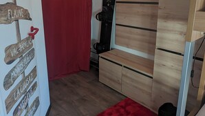 Une chambre avec une armoire en bois, un rideau rouge et une planche de snowboard appuyée contre le mur.