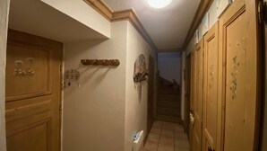 Un pasillo estrecho con puertas de madera, un radiador y una escalera que sube a otro piso.