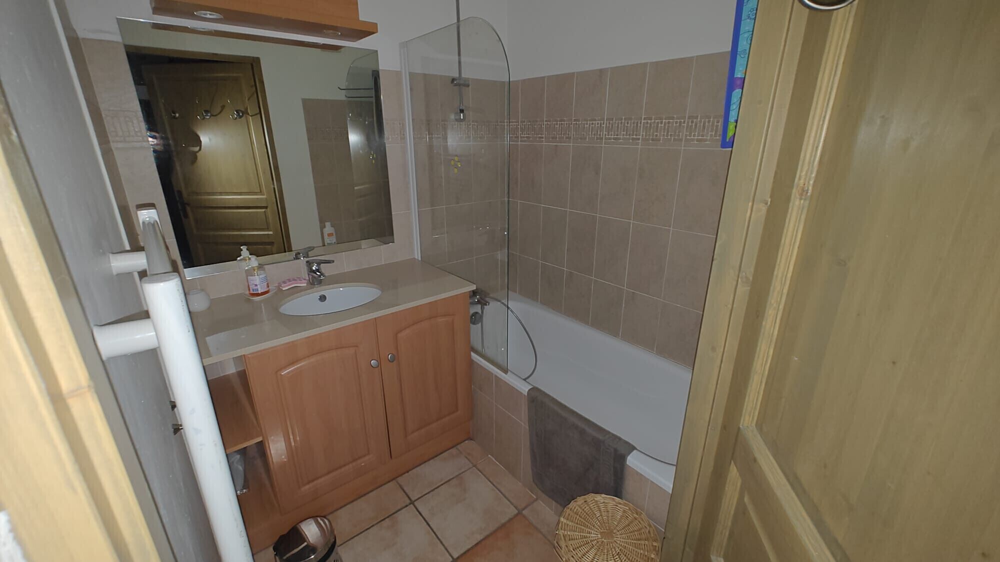 A bathroom with a sink, mirror, and shower.