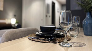 Una mesa de comedor con un bol, una copa de vino y cubiertos, sobre un mantel tejido.