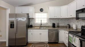 A modern kitchen with white cabinets, stainless steel appliances, a clock, and a window. - Beautifully furnished house located in sought after Rosedale community. (Rosedale)