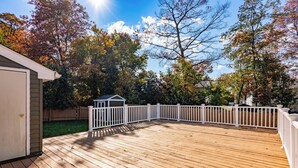 A wooden deck with a white railing, surrounded by trees and a small shed. - Beautifully furnished house located in sought after Rosedale community. (Rosedale)