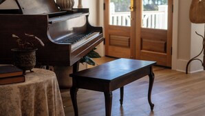 Un piano de cola, una mesa de madera y una escalera de madera en una habitación con suelo de madera.