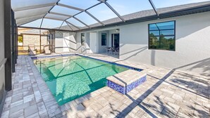 A swimming pool with a glass ceiling, tiled flooring, and a view of the outside. - Sweet Retreat, Sleeps 6, heated salt pool (Port Charlotte)