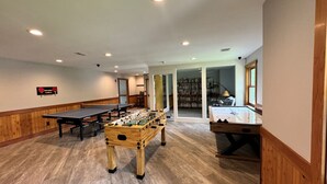 Een ruime kamer met een tafelvoetbaltafel, een pingpongtafel en een tafelvoetbaltafel met een houten onderstel.