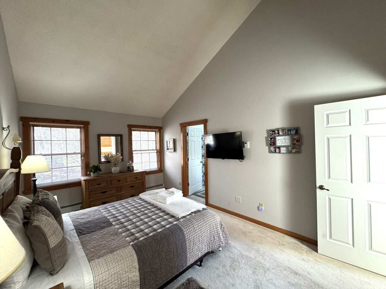 Un dormitorio con una cama grande, cómoda y televisor montado en la pared.