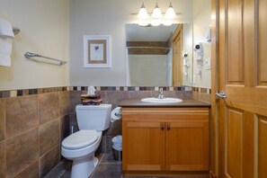 A bathroom with a toilet, sink, and shower area. - Views of Red Mountain, 7 minute walk to lifts! (Rossland)
