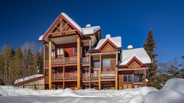 Ein mehrstöckiges Holzhaus mit Balkonen, umgeben von Schnee.
