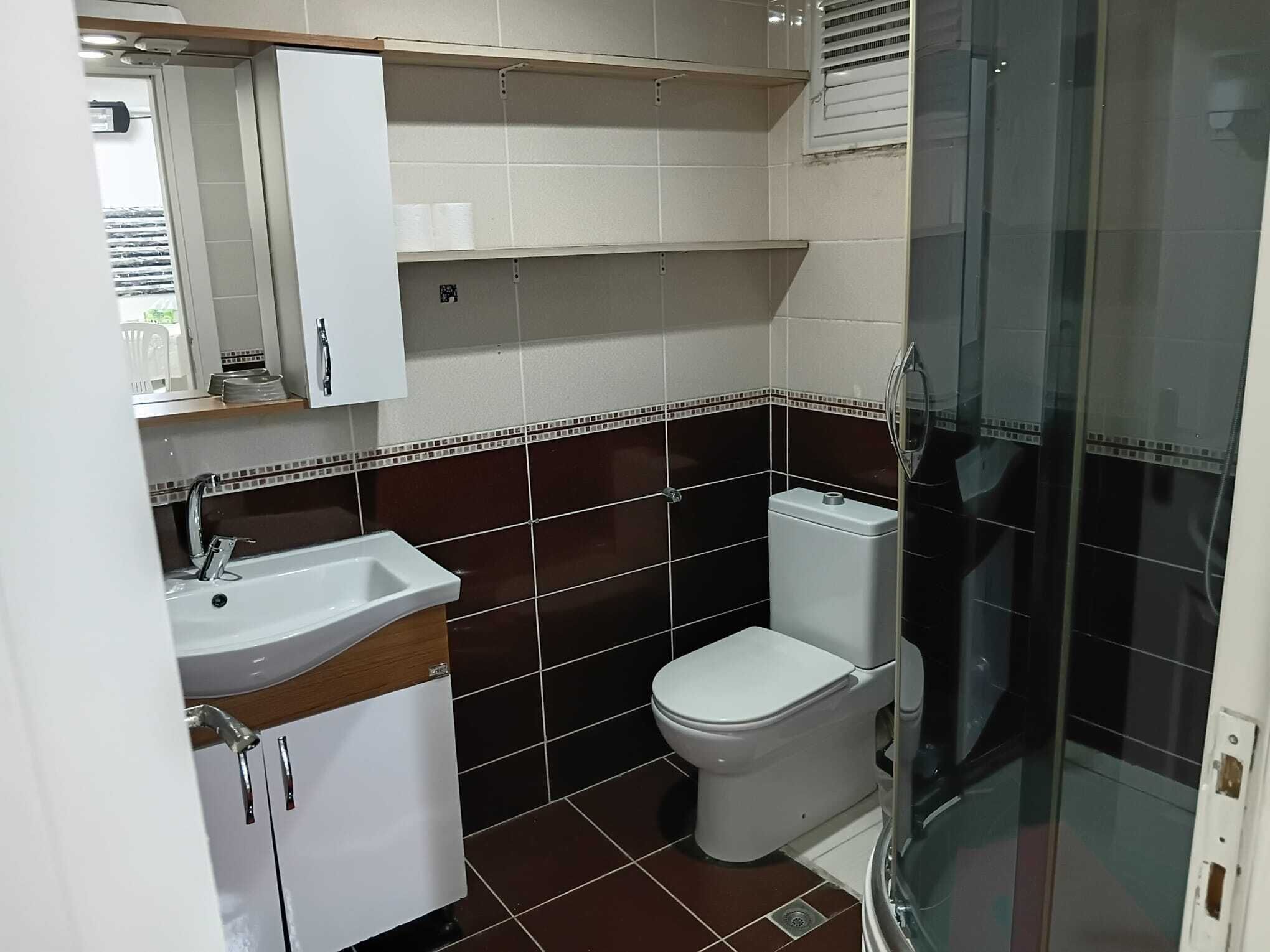 A bathroom with a white sink, a toilet, and a glass shower enclosure.