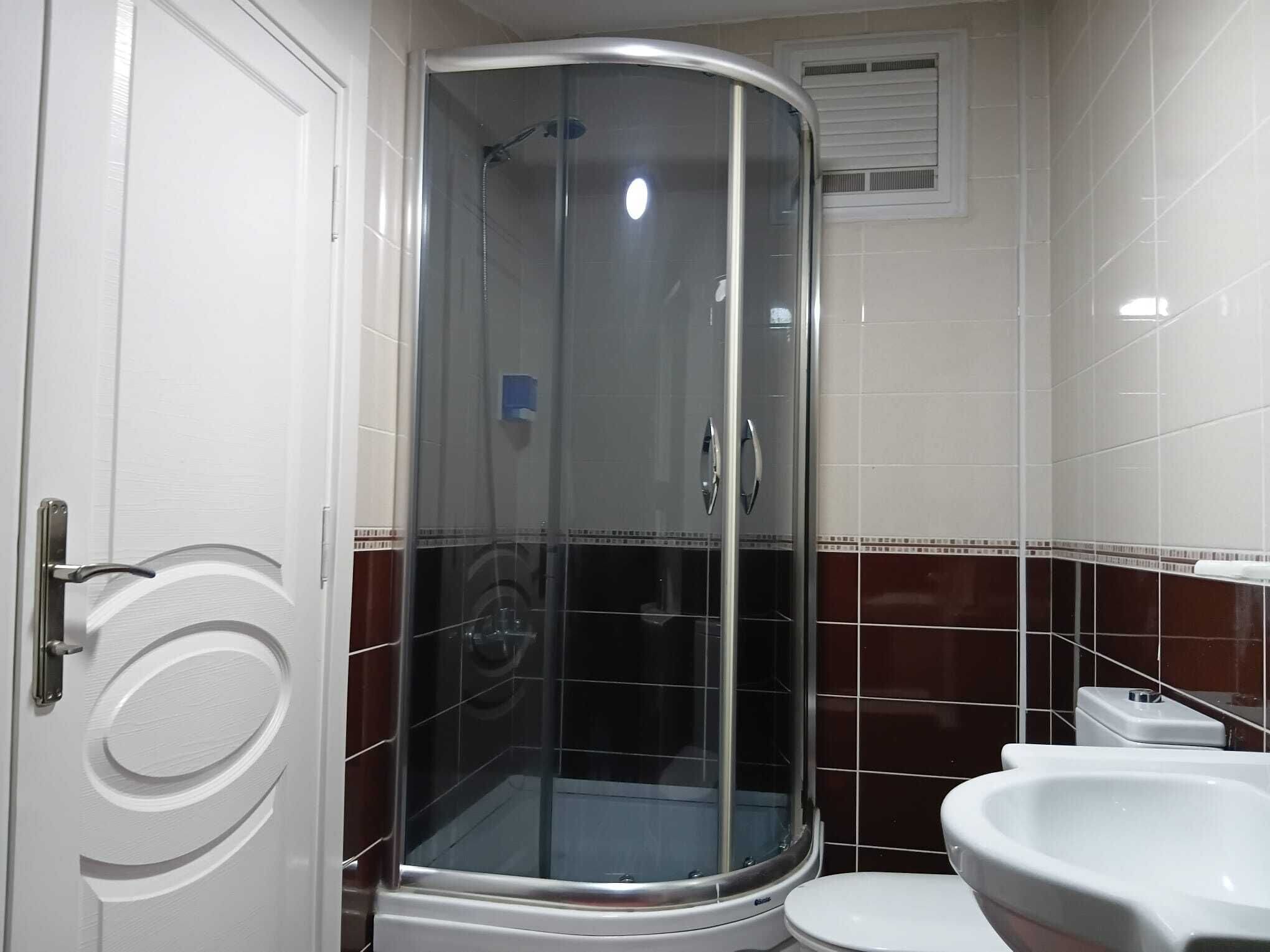 A bathroom with a glass-enclosed shower, a white toilet, and a white sink.