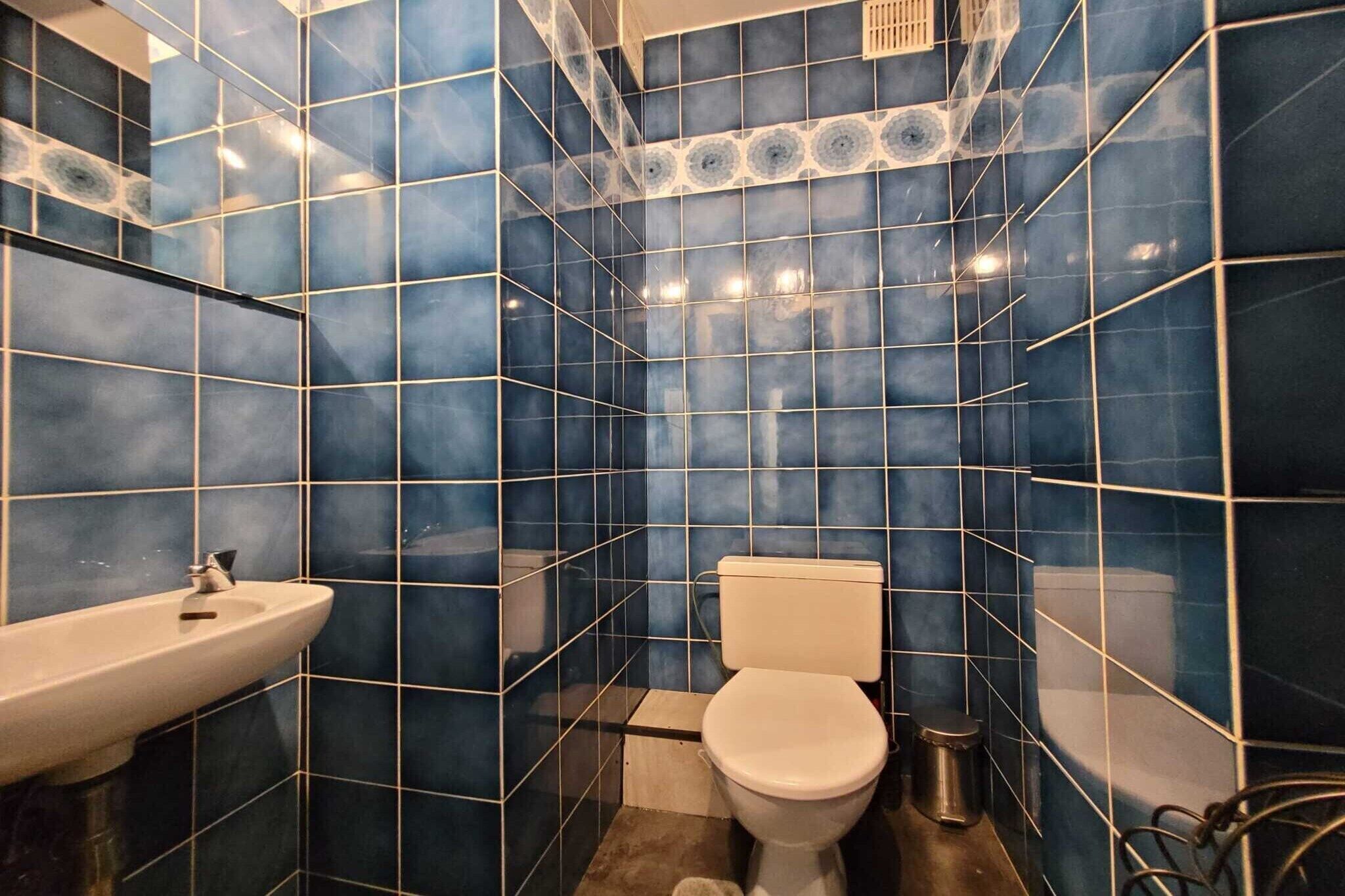 A bathroom with blue tiles, a white sink, and a toilet.