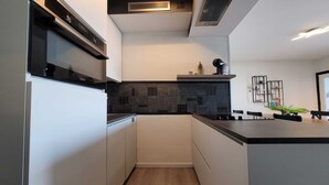 Una cocina moderna con armarios blancos, encimera negra y salpicadero de azulejos.