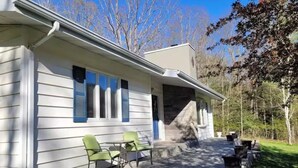 Ein Haus mit überdachter Terrasse, Sitzgelegenheiten im Freien und einer Steintreppe, die zum Eingang führt.