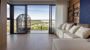 A spacious living room with a large sliding glass door leading to a balcony, a white sofa, and a wooden bookshelf. - NEW Apartment, best rooftop pool view, Cartagena (Cartagena)