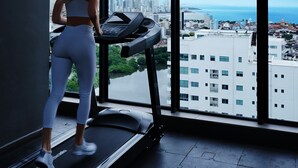 A woman running on a treadmill in a room with large windows overlooking a cityscape and the sea. - NEW Apartment, best rooftop pool view, Cartagena (Cartagena)