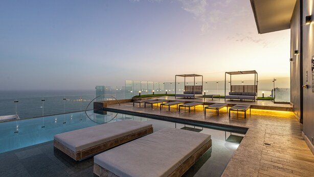 A modern infinity pool with lounge chairs and a glass railing overlooking the sea. - NEW Apartment, best rooftop pool view, Cartagena (Cartagena)