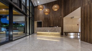 A modern reception area with a marble reception desk, wooden panel walls, and three woven pendant lights. - NEW Apartment, best rooftop pool view, Cartagena (Cartagena)