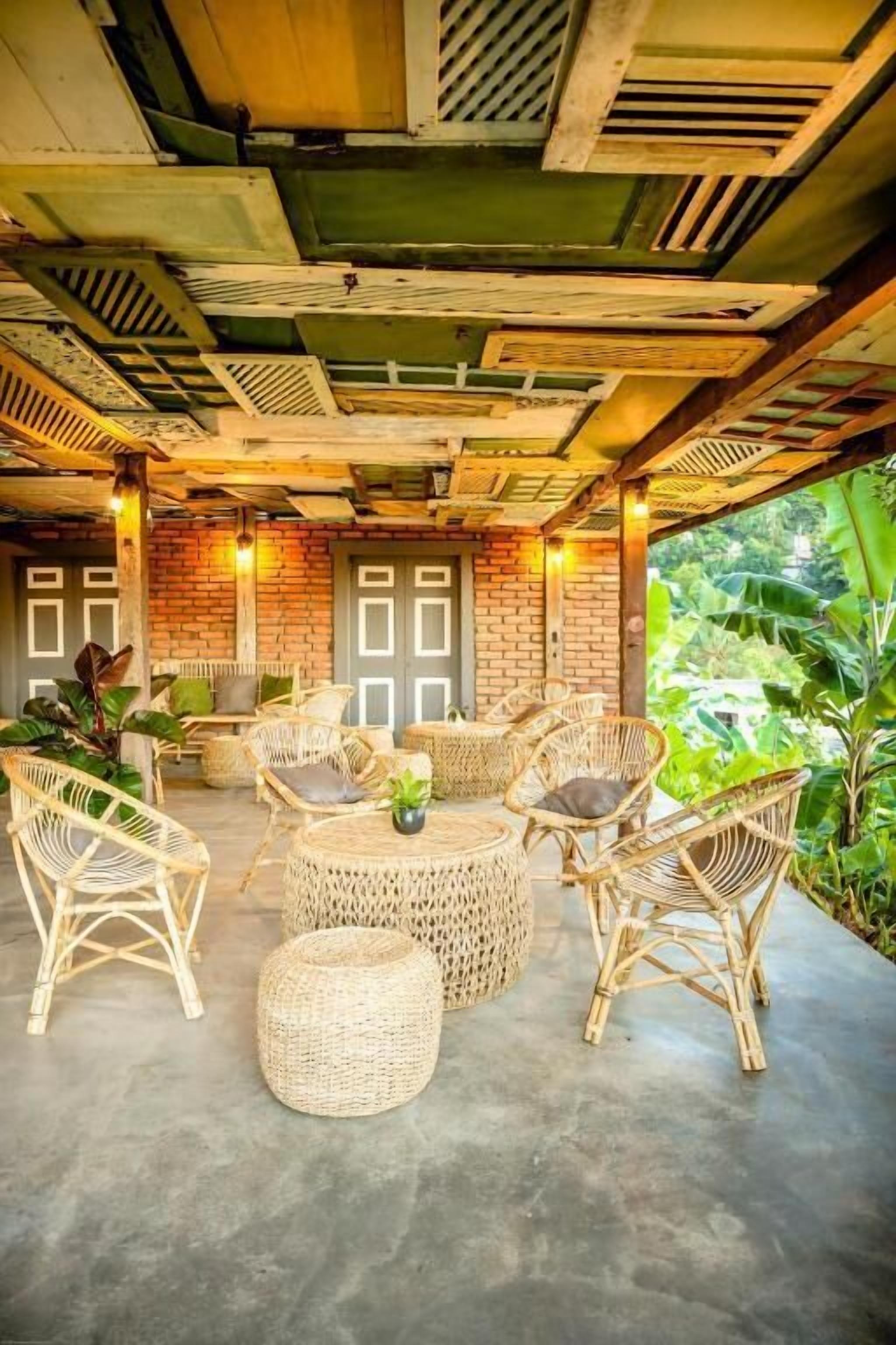 An outdoor seating area with wicker furniture and a brick wall backdrop.