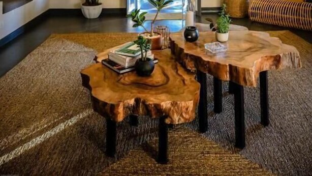 Une pièce dotée d’un grand luminaire suspendu en fibres tressées, de tables en bois et offrant une vue sur la verdure environnante.