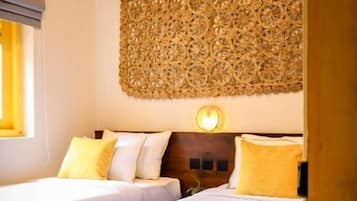 A hotel room with two beds, a decorative wall panel, and a bedside lamp.