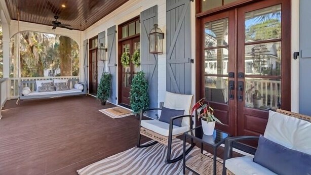 A covered porch with wooden flooring, a bench, two chairs, and a table. - Two Homes · Walk to Old Town · Fire Pit · EV (Bluffton)