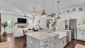 A modern kitchen with white cabinets, a marble countertop, and stainless steel appliances. - Two Homes · Walk to Old Town · Fire Pit · EV (Bluffton)