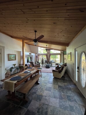 A spacious room with a wooden ceiling, a large dining table, and a cozy seating area with a sofa and chairs. - Rustic Lakefront Retreat (Leesville)