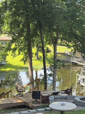 A deck with outdoor furniture overlooking a pond and a grassy area.