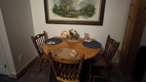 A dining table with a painting above it, surrounded by wooden chairs.