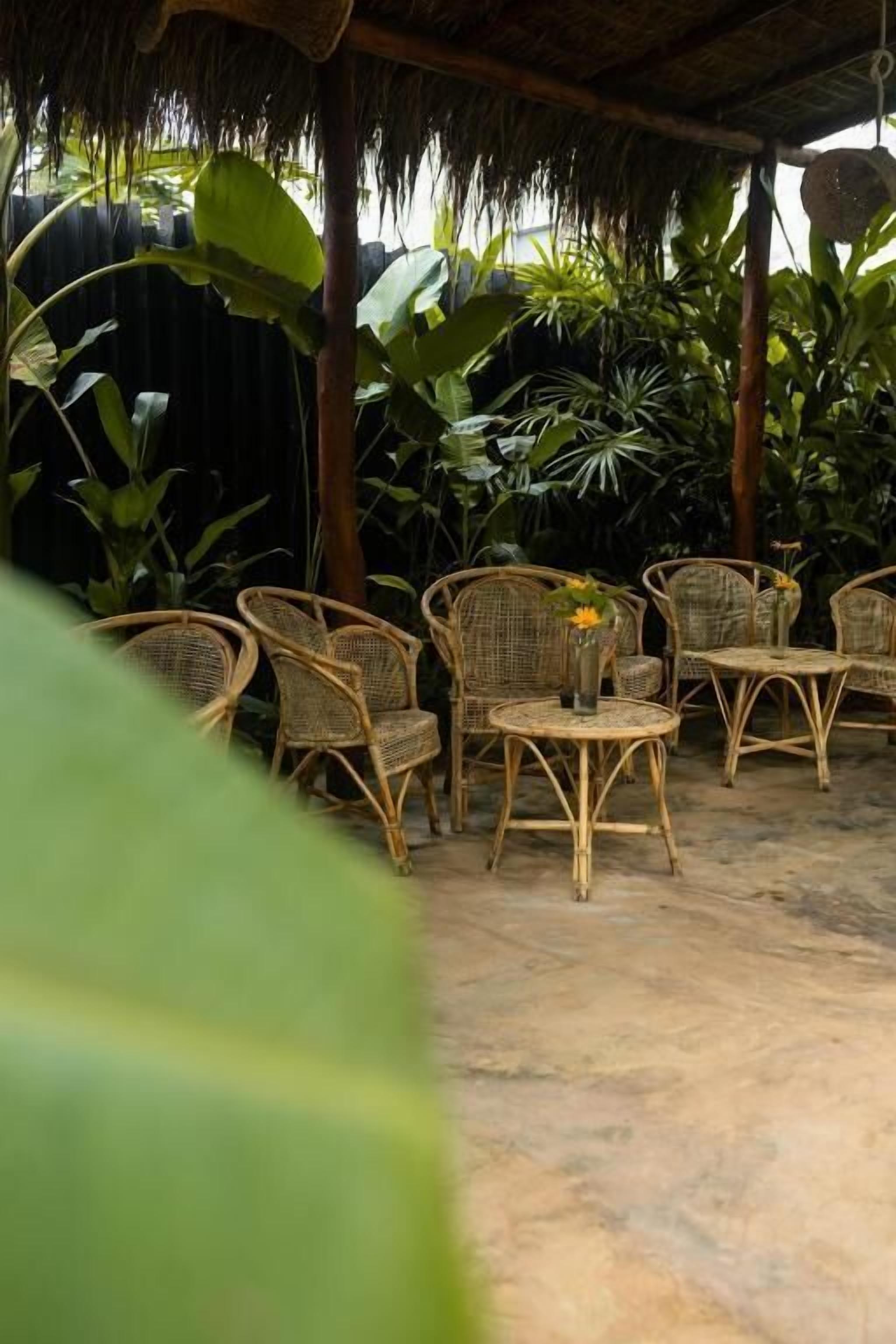 A covered outdoor seating area with wicker furniture and a thatched roof.