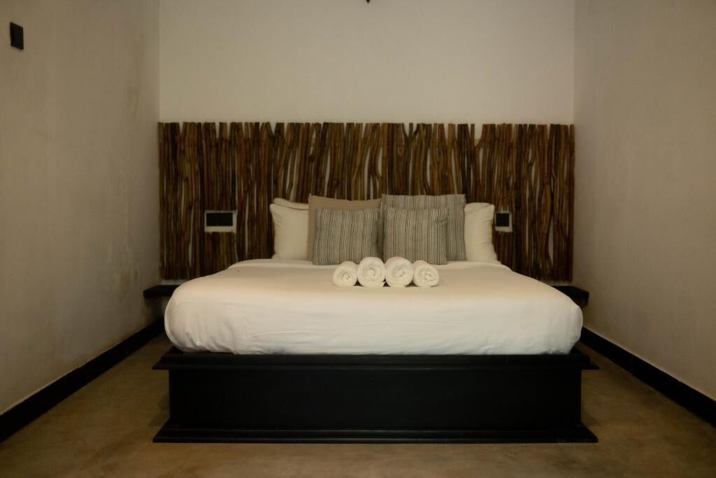Un dormitorio moderno con una cama grande, cabecera de madera y base plataforma negra.