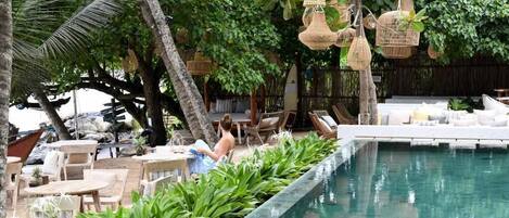 Una piscina al aire libre, sombrillas, sillones reclinables de piscina