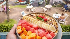 A bowl of fruit salad with a beach view in the background. - Banana Bunks Mirissa (Mirissa)