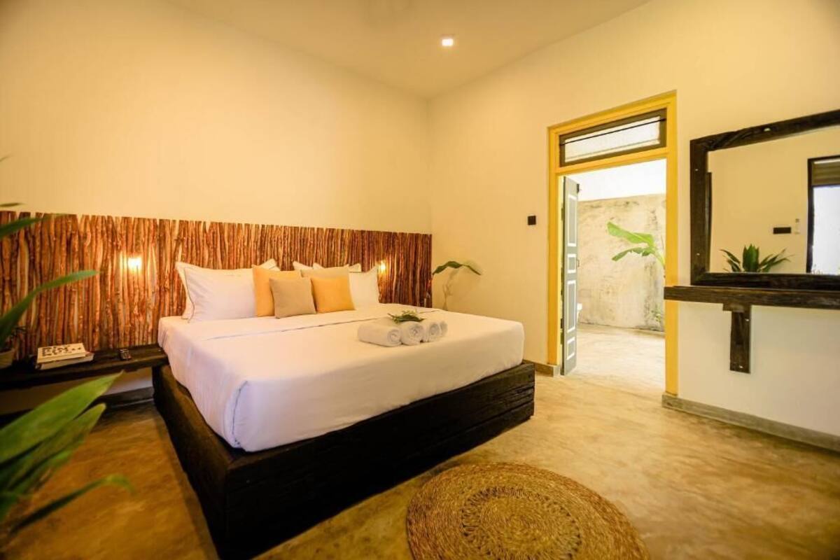A bedroom with a bed, bedside table, and a mirror.