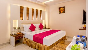 Une chambre d’hôtel moderne avec un grand lit, des tables de chevet, un bureau et un ventilateur de plafond.