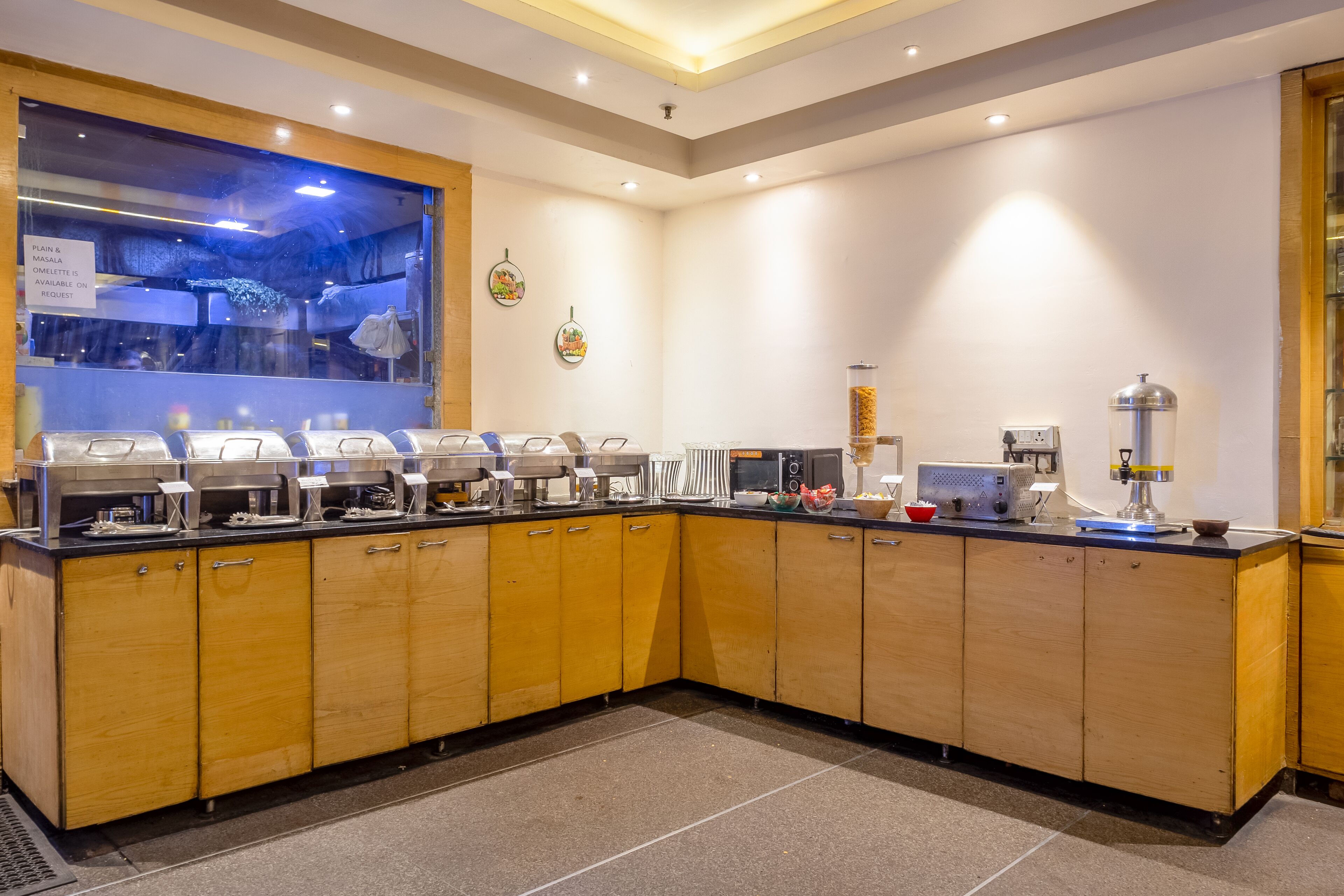 A modern kitchen with a buffet setup, including a glass display case and various food stations.