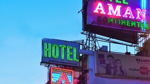 Une enseigne au néon pour l’hôtel Aman Continental, sur laquelle on peut clairement lire son nom et qui offre une vue dégagée sur les environs.