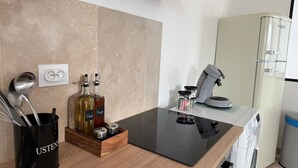 A modern kitchen with a black countertop, a coffee machine, a refrigerator, and a wooden utensil holder. - Spacious and Bright New T3 (Évreux)