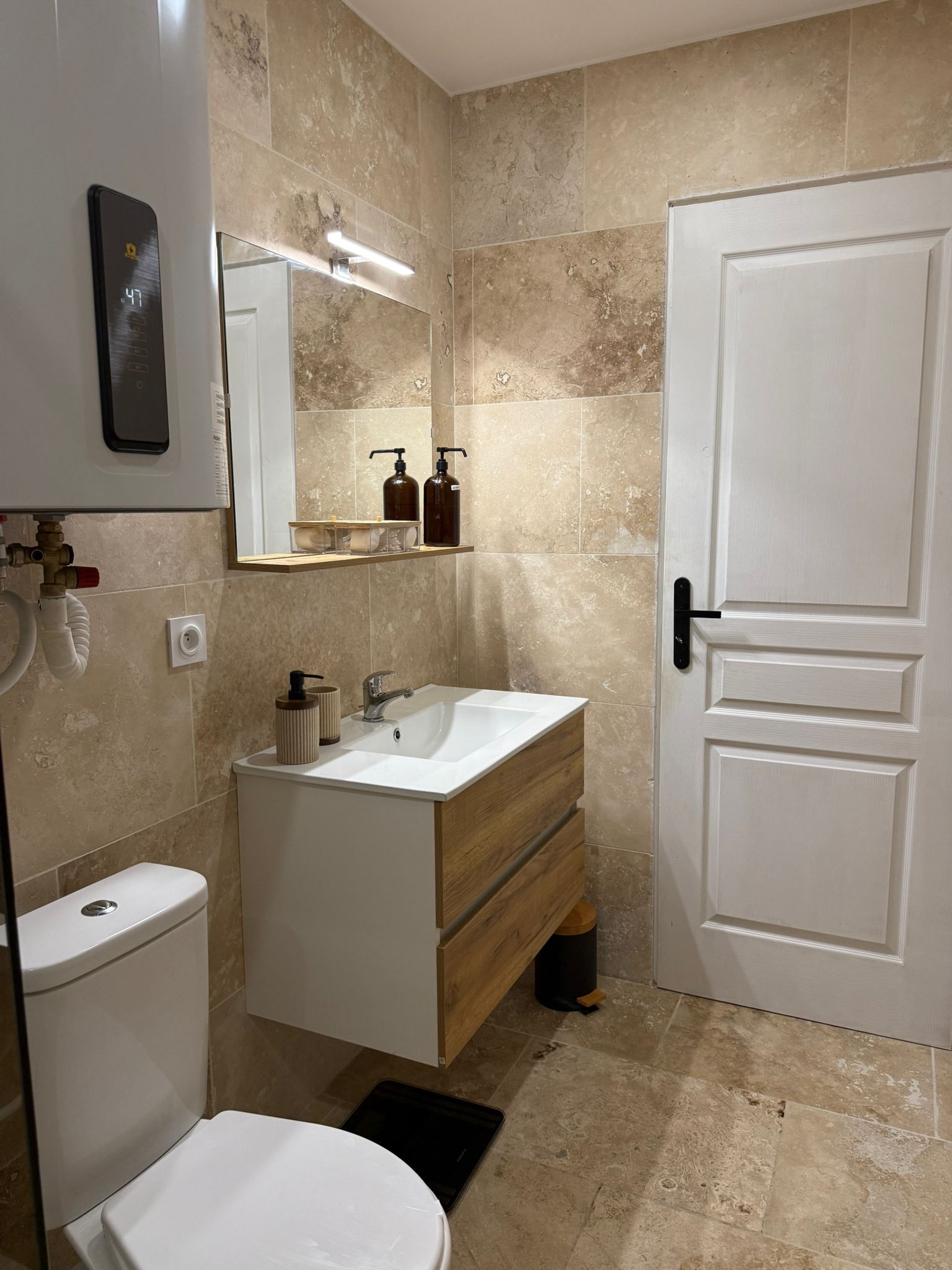 Ein modernes Badezimmer mit einer weißen Toilette, einem hölzernen Waschtisch mit Waschbecken und einem Spiegel darüber.