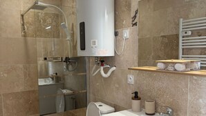 A modern bathroom with a shower, toilet, and sink. - Spacious and Bright New T3 (Évreux)