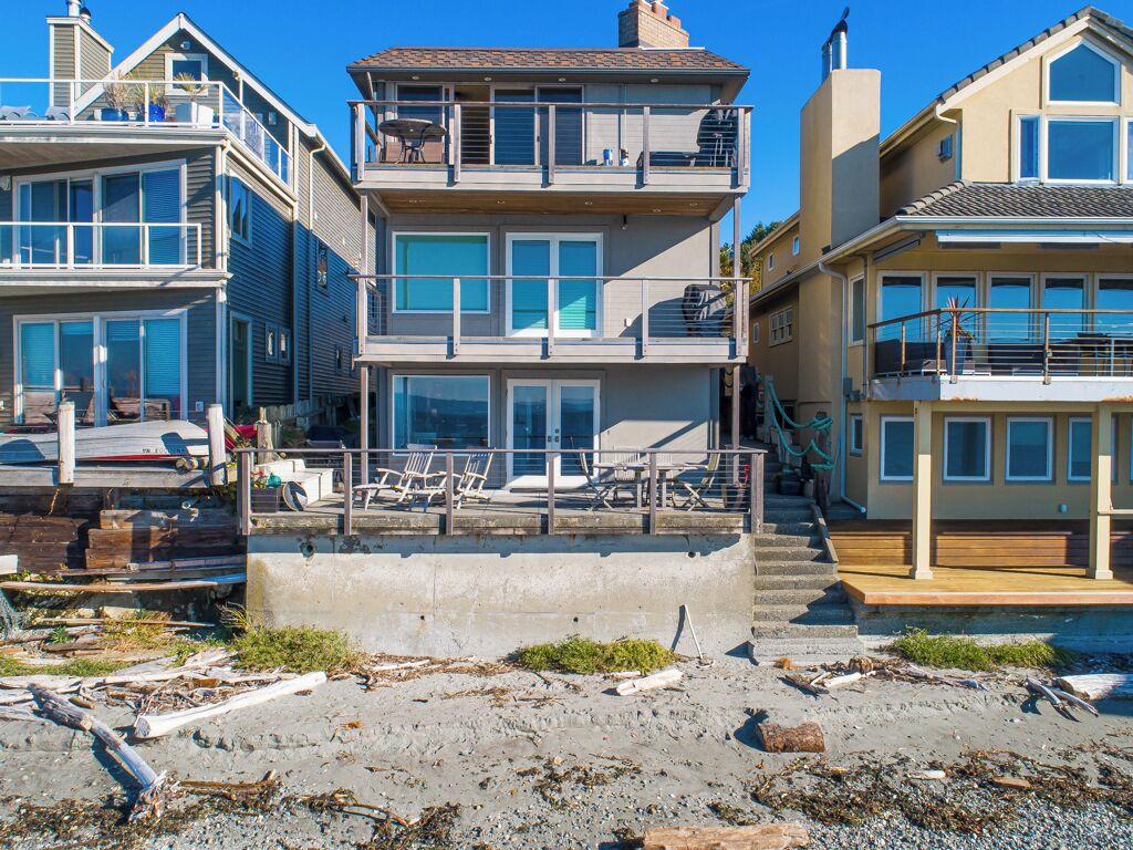 Una propiedad frente a la playa con un edificio de dos pisos, un balcón y una escalera que conduce al piso superior.