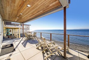 A wooden deck with lounge chairs overlooking a beach.