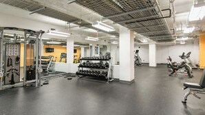 A gym with various exercise equipment, including dumbbells, treadmills, and weight machines. - Relax & Recharge 1br Downtown Loft w Private Patio (Des Moines)