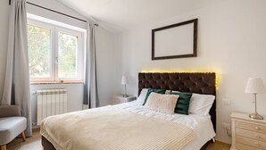 A neatly arranged bedroom with a large bed, a bedside table, a chair, and a window with curtains. - Charming Tuscany Villa w/ Private Infinity Pool (Castel del Piano)