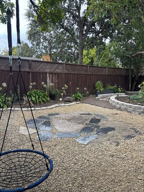 A backyard with a swing set, a wooden fence, and a garden area with various plants. - Lovely 1-bedroom studio in peaceful Santa Rosa perfect for your stay (Santa Rosa)